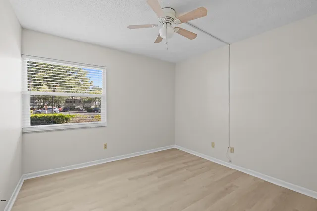 an empty room with chandelier fan and windows
