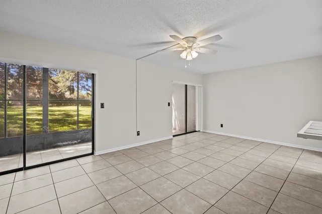 a view of an empty room with chandelier fan and a window