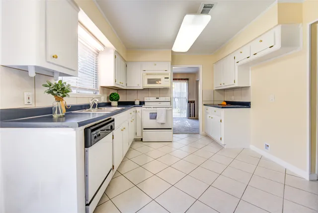 a kitchen with granite countertop white cabinets and white appliances