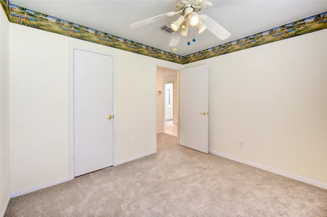 an empty room with a chandelier fan and wooden floor