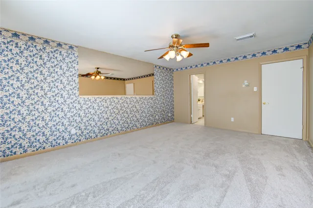 an empty room with a chandelier fan and wooden floor