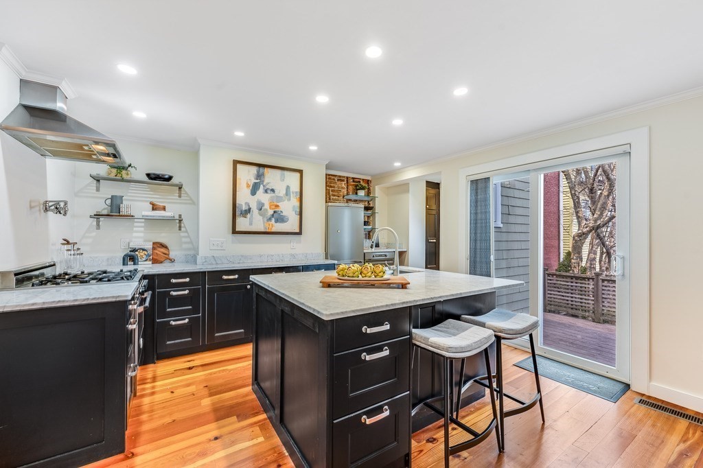 73 Gore Street Cambridge, MA 02141 - Photo 10 of 41 a kitchen with stainless steel appliances granite countertop table chairs sink and wooden floor