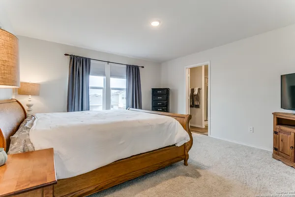 a bed sitting in a spacious bedroom next to a window and dresser