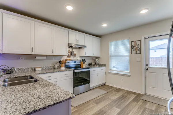 a kitchen with granite countertop white cabinets and white appliances