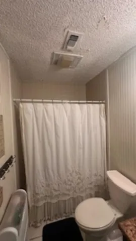 a bathroom with a toilet and a shower curtain