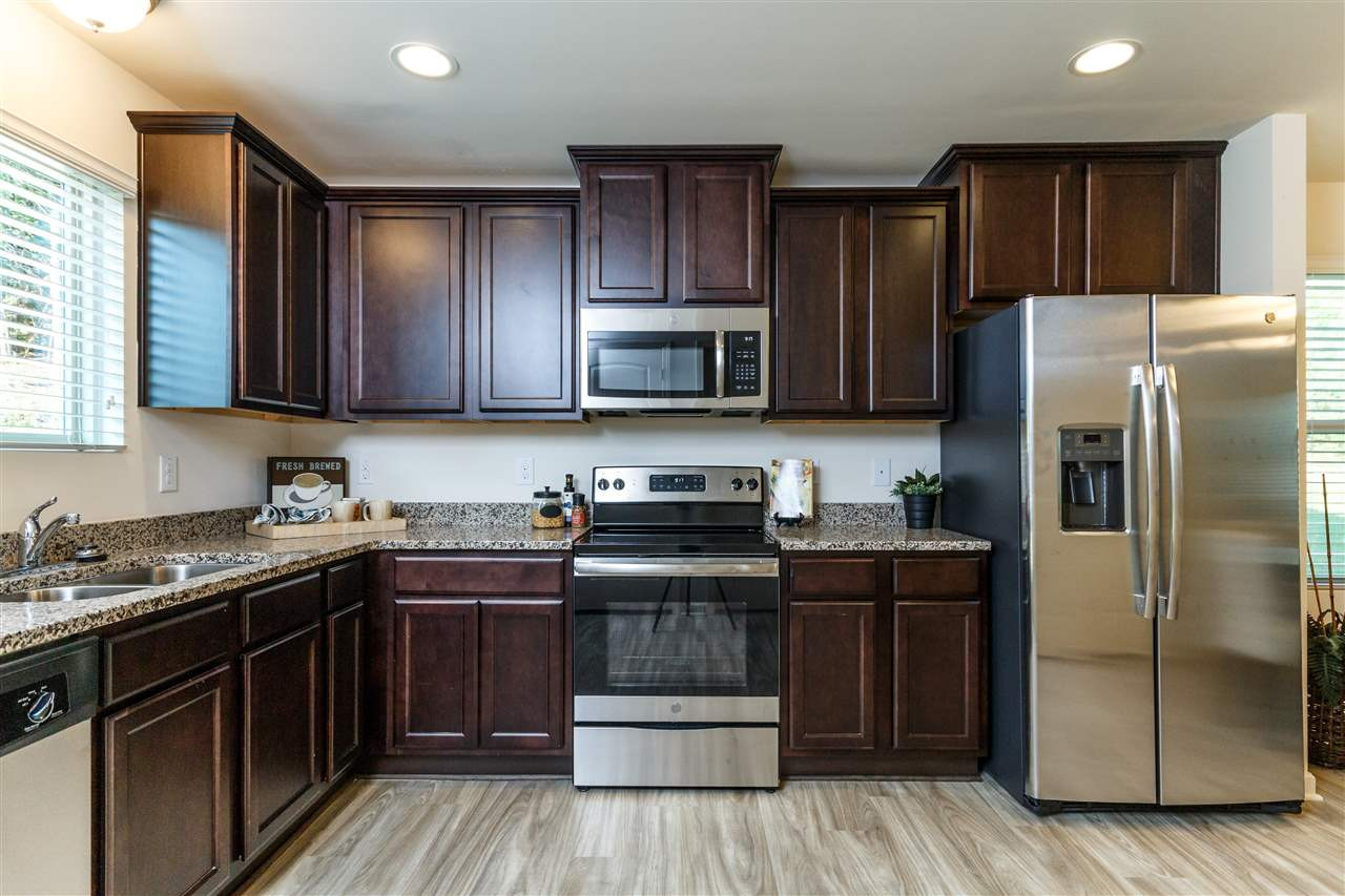 241 Spark Street Raleigh, NC 27606 - Photo 8 of 25 a kitchen with stainless steel appliances granite countertop wooden cabinets a stove a refrigerator and a sink with wooden floor