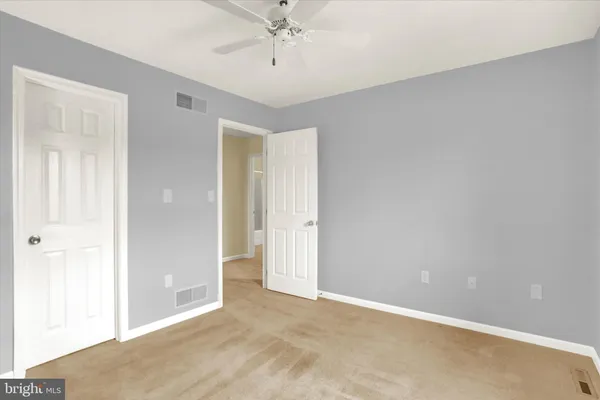 a view of an empty room and chandelier fan