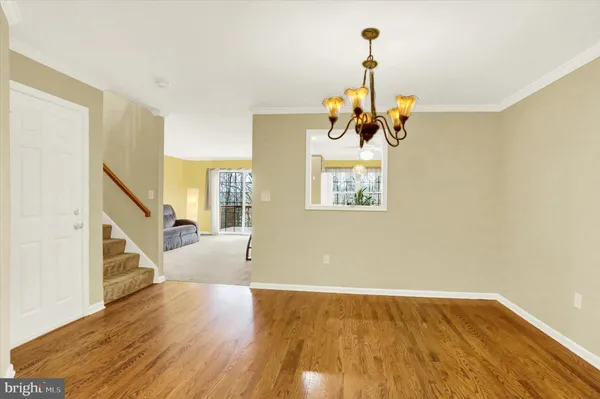 a view of a room with wooden floor staircase and a chandelier