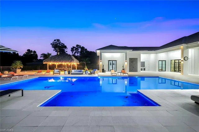 a view of pool with lawn chairs and wooden fence