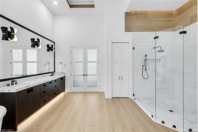a spacious bathroom with a granite countertop sink a mirror a bathtub and shower