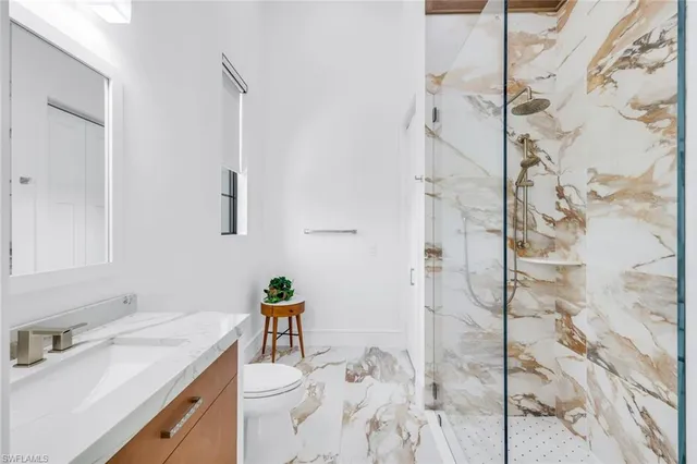 a bathroom with a granite countertop sink a toilet and shower