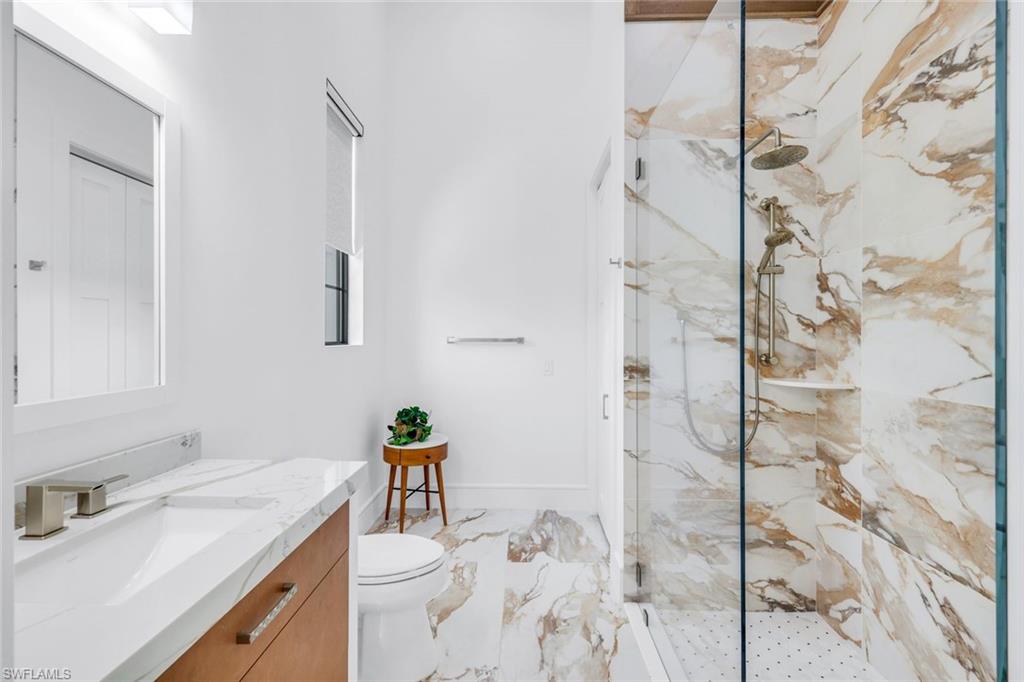 6677 Hunters Road Naples, FL 34109 - Photo 38 of 50 a bathroom with a granite countertop sink a toilet and shower