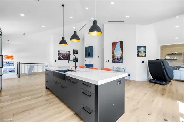 a large kitchen with stainless steel appliances a stove a sink a refrigerator and a dining table with wooden floor