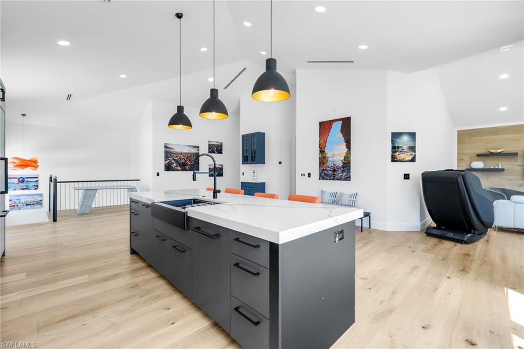 6677 Hunters Road Naples, FL 34109 - Photo 40 of 50 a large kitchen with stainless steel appliances a stove a sink a refrigerator and a dining table with wooden floor