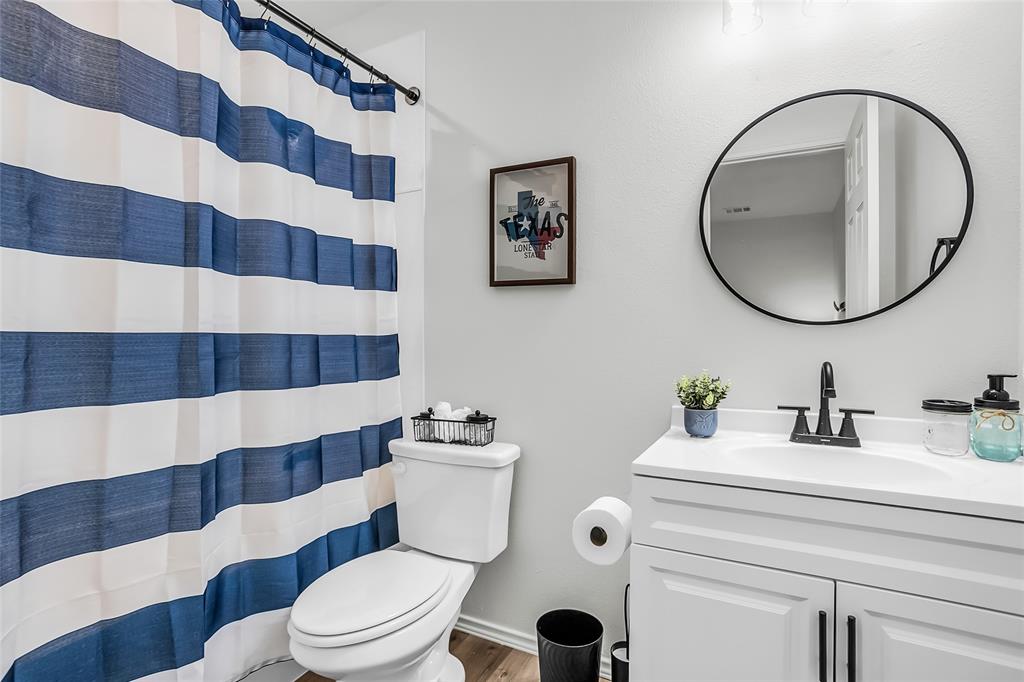 308 South 3rd Street Bonham, TX 75418 - Photo 19 of 19 a bathroom with a sink a toilet a mirror and shower curtain