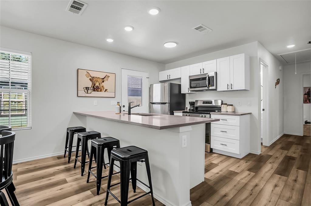 308 South 3rd Street Bonham, TX 75418 - Photo 2 of 19 a kitchen with stainless steel appliances granite countertop a stove top oven a sink a dining table and chairs with wooden floor