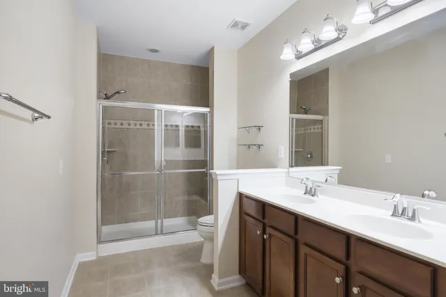 a bathroom with a double vanity sink mirror and toilet