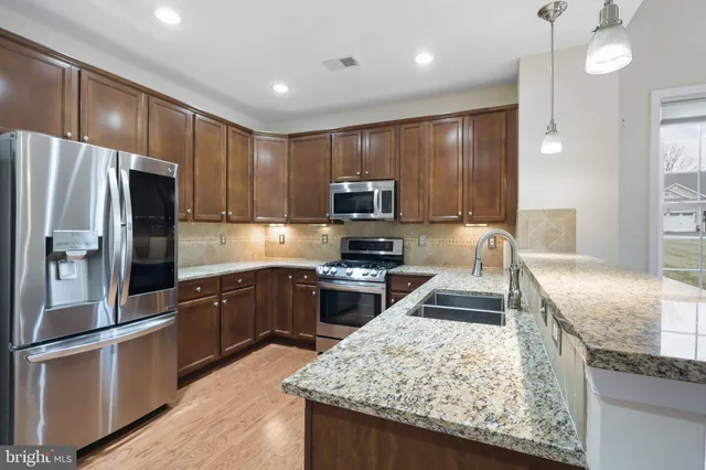 a kitchen with granite countertop wooden cabinets a refrigerator and a stove top oven