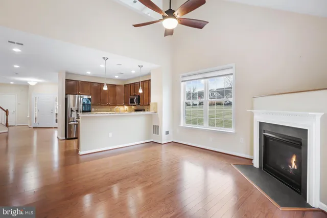 a view of an empty room with wooden floor and a kitchen