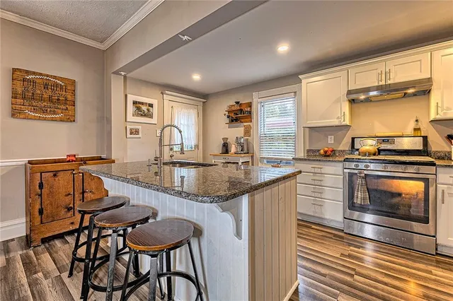 a kitchen with granite countertop a stove and white cabinets