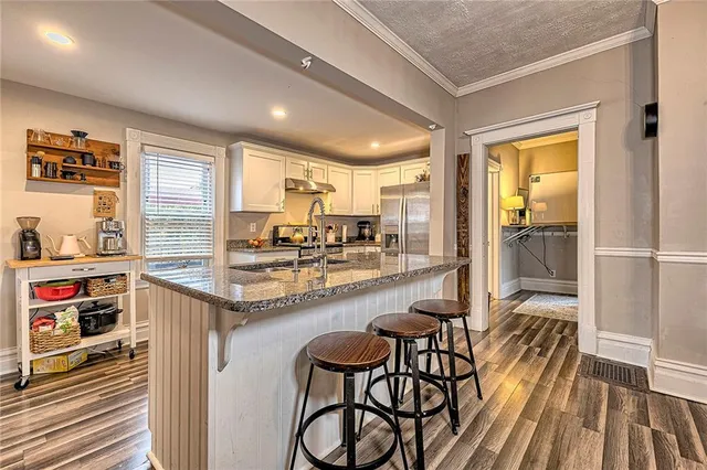 a kitchen with granite countertop a table chairs stove and a sink