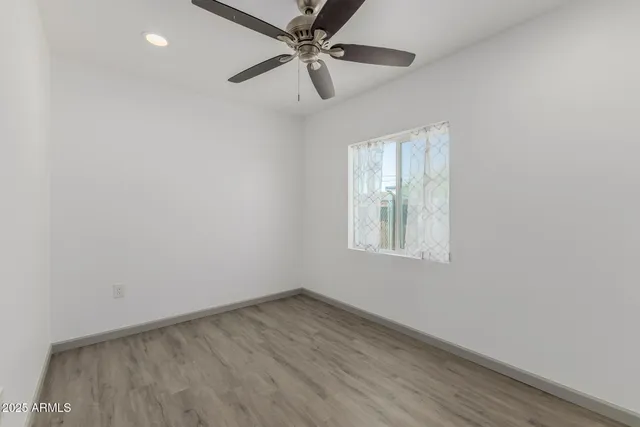 an empty room with a window and a fan