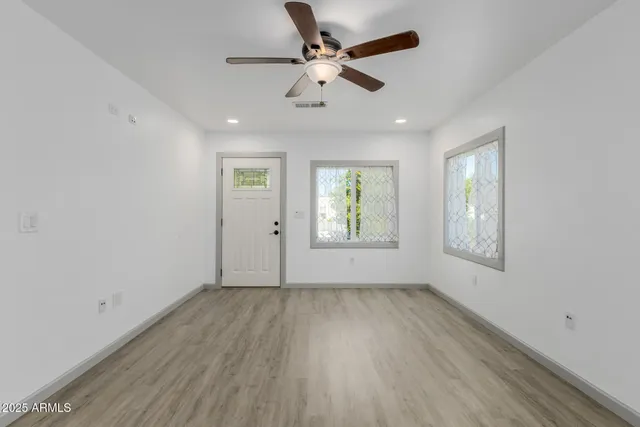 a view of an empty room with a window and wooden floor