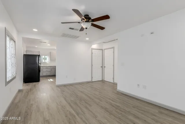 a view of an empty room with a ceiling fan and wooden floor