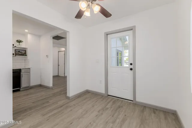 an empty room with wooden floor and a kitchen space