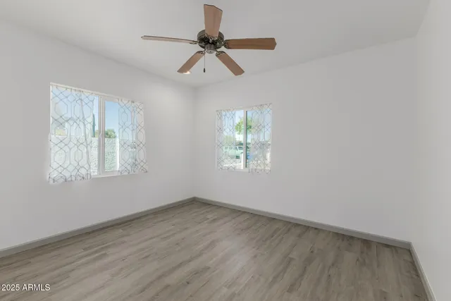 a view of empty room with wooden floor and fan