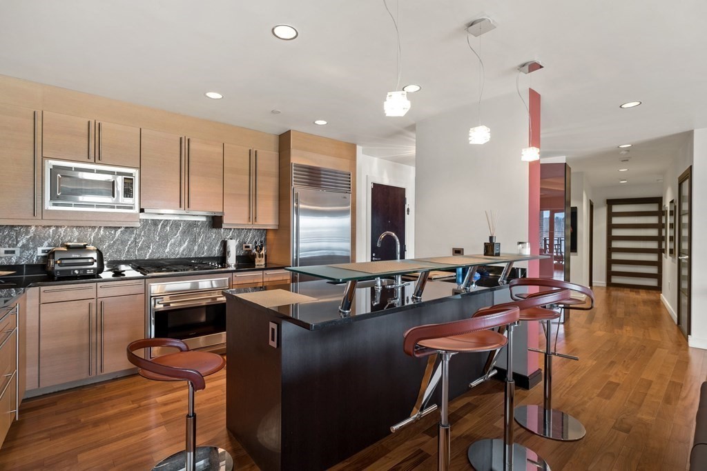 2400 Beacon Street, Unit 401 Boston, MA 02467 - Photo 9 of 35 a kitchen with stainless steel appliances granite countertop a stove top oven a sink dishwasher a dining table and chairs with wooden floor