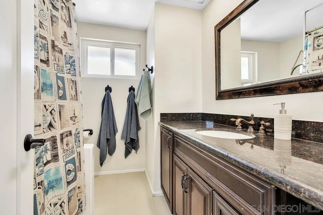 1668 Olmeda Street Encinitas, CA 92024 - Photo 18 of 42 a bathroom with a granite countertop sink a mirror and shower