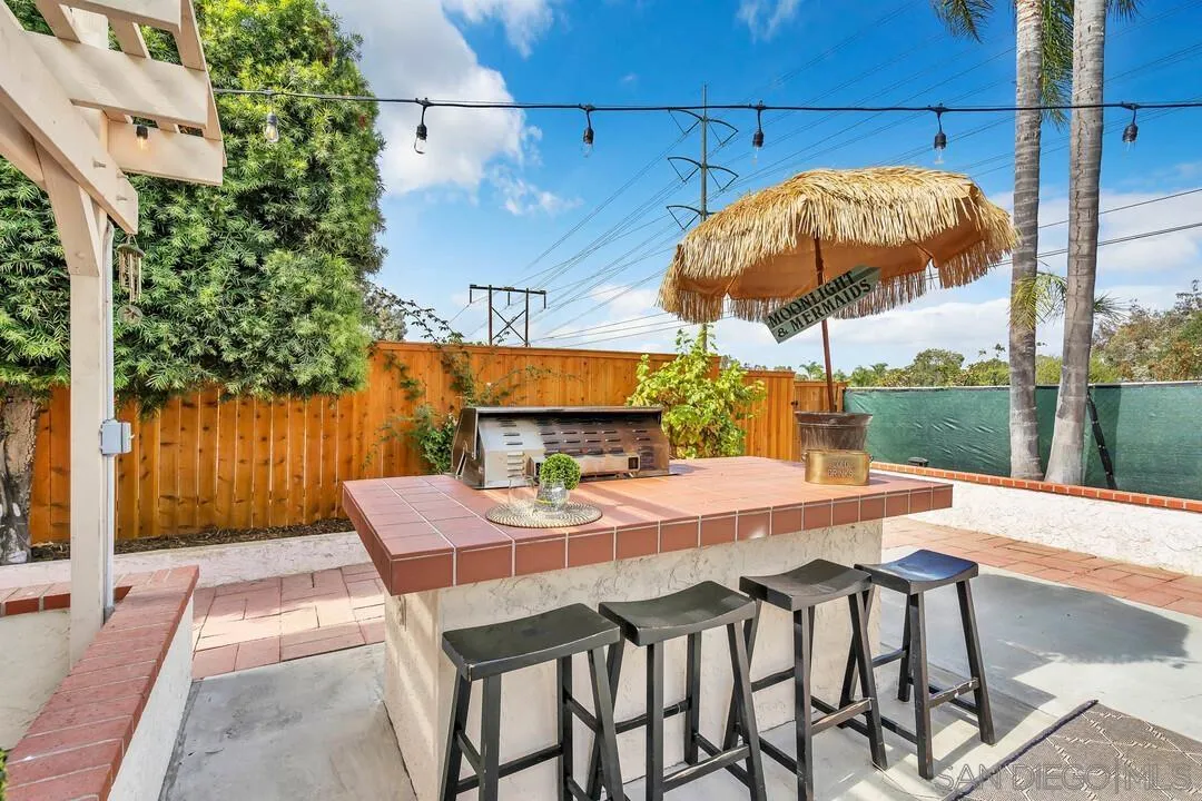 1668 Olmeda Street Encinitas, CA 92024 - Photo 35 of 42 a view of a patio with a table and chairs under an umbrella with a small yard