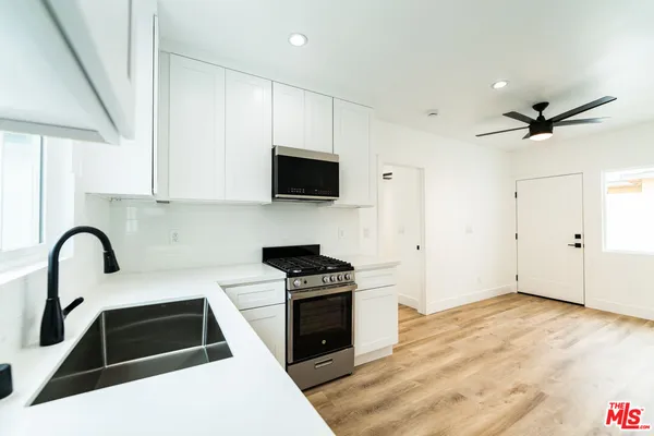 a kitchen with granite countertop a stove a sink and a microwave