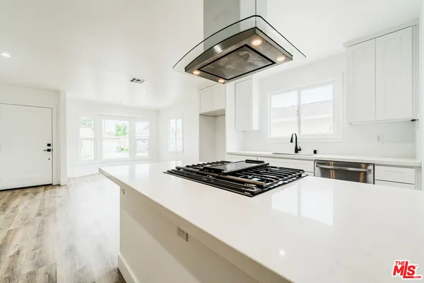 a kitchen with stainless steel appliances granite countertop a stove a sink and white cabinets