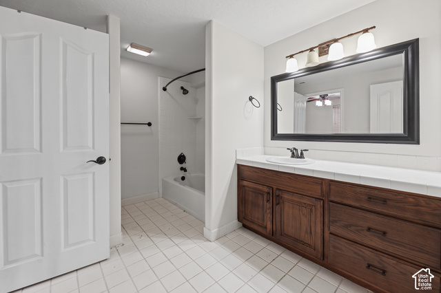 10664 Trail Ridge Circle Sandy, UT 84092 - Photo 49 of 113 White tile flooring, wood-finish vanity with countertop, framed mirror, and a built-in tub with shower