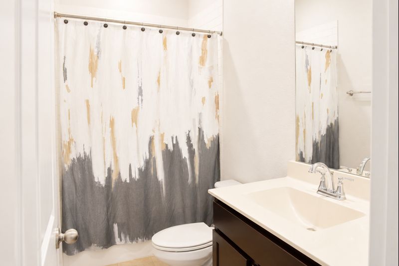 693 Durian Loop Buda, TX 78610 - Photo 6 of 27 A well-appointed bathroom offers a convenient toilet and a vanity with an integrated sink and mirror.
