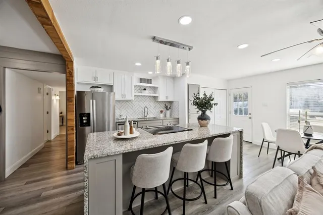 a kitchen with granite countertop kitchen island stainless steel appliances a table and chairs in it