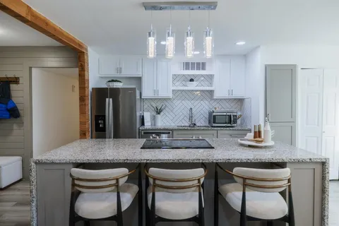 a kitchen with stainless steel appliances granite countertop a table chairs stove and refrigerator