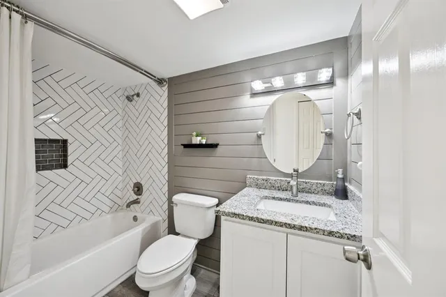 a bathroom with a granite countertop toilet a sink and a mirror