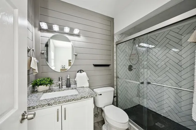 a bathroom with a granite countertop sink mirror vanity and toilet