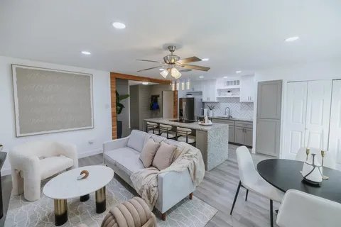 a living room with furniture a flat screen tv and kitchen view