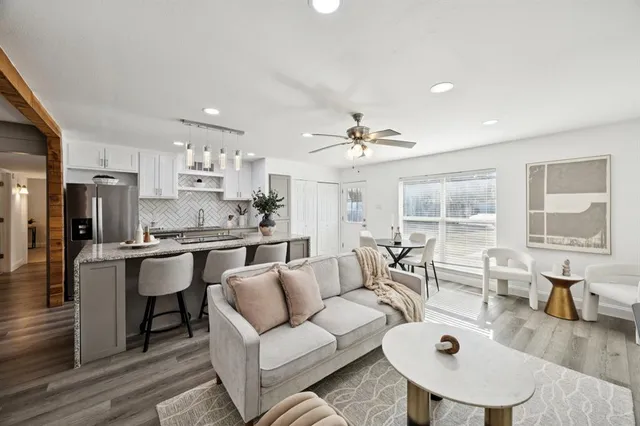 a living room with stainless steel appliances furniture and a kitchen view