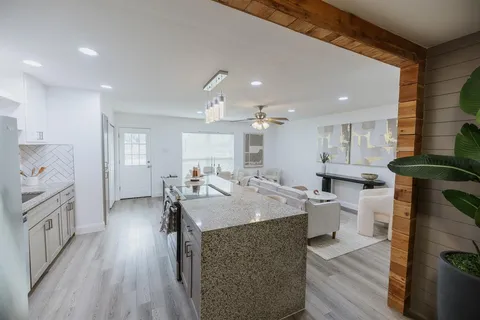 a large kitchen with kitchen island a sink dishwasher a stove a dining table and chairs with wooden floor