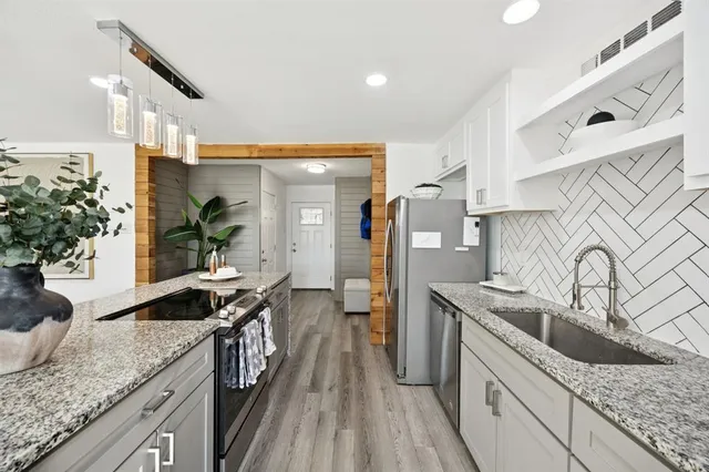 a kitchen with granite countertop a sink stove and cabinets
