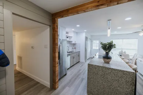 a kitchen with stainless steel appliances granite countertop a refrigerator a sink and white cabinets