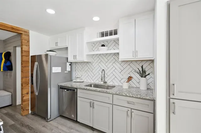 a kitchen with stainless steel appliances granite countertop a refrigerator sink and white cabinets