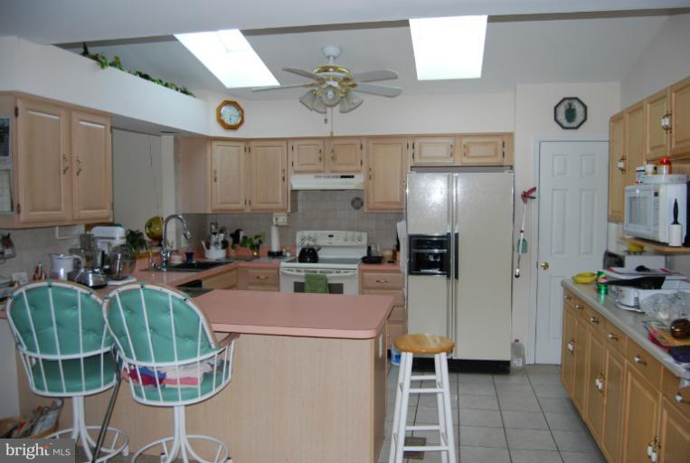 4308 Spring Avenue Halethorpe, MD 21227 - Photo 6 of 21 a kitchen with stainless steel appliances kitchen island granite countertop a refrigerator a stove a sink dishwasher and white cabinets with wooden floor