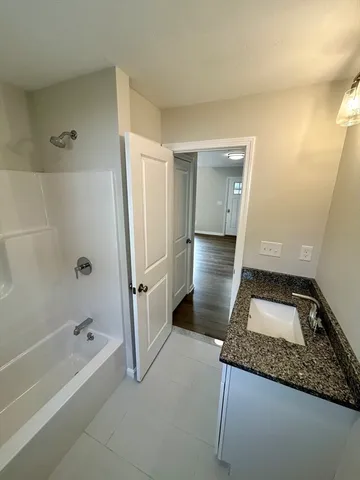 a bathroom with a granite countertop sink a toilet and bathtub