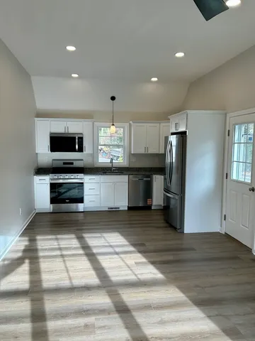 a large kitchen with stainless steel appliances kitchen island granite countertop a refrigerator and a stove top oven